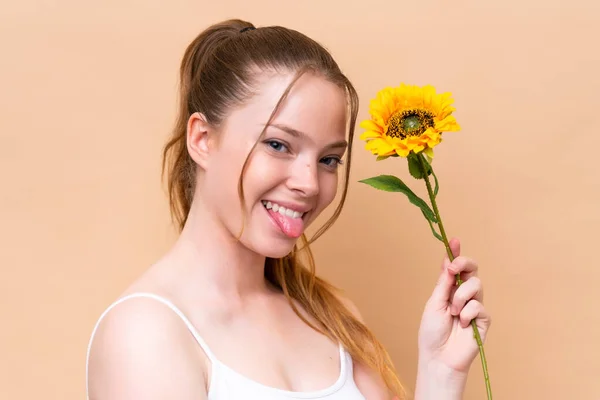 Młoda Kaukaska Dziewczyna Odizolowana Beżowym Tle Trzymająca Słonecznik Podczas Uśmiechu — Zdjęcie stockowe