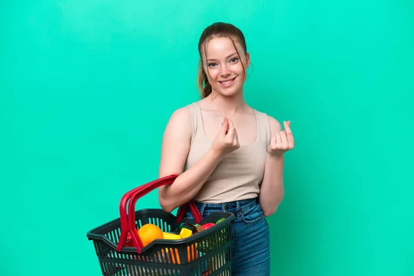 Young Woman Holding Shopping Basket Full Food Isolated Green Background — Stok fotoğraf