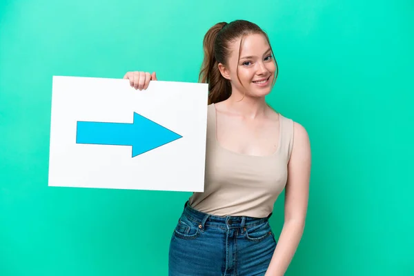 Young Caucasian Woman Isolated Green Background Holding Placard Arrow Symbol — Stockfoto