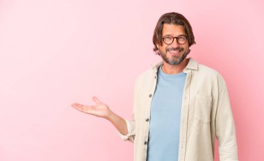 Kıdemli Hollandalı, pembe arka planda izole edilmiş. Elinde bir ilan vermek için avucunda hayali bir alan tutuyor.