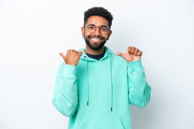 Beyaz arka planda izole edilmiş genç Brezilyalı bir adam bir ürün sunmak için kenarı işaret ediyor