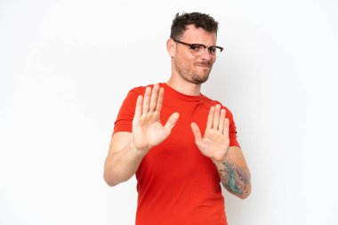 Beyaz arka planda soyutlanmış beyaz tenli yakışıklı adam ellerini öne uzatıyor.