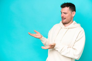 Mavi arka planda mahsur kalmış beyaz, yakışıklı genç bir adam.