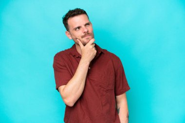 Beyaz tenli yakışıklı bir adam mavi arka planda izole edilmiş ve yukarı bakıyor.