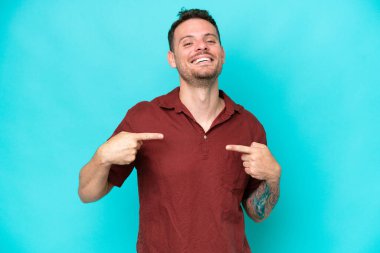 Mavi arka planda soyutlanmış, gururlu ve kendini beğenmiş beyaz, yakışıklı genç bir adam.