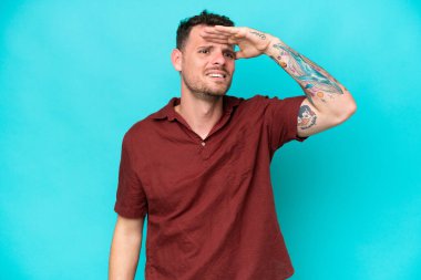 Beyaz tenli yakışıklı adam mavi arka planda izole edilmiş. Bir şeye bakmak için uzaklara bakıyor.