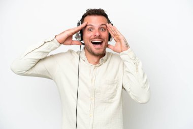 Tele pazarlamacı, beyaz arka planda, sürpriz bir ifadeyle, kulaklıkla çalışan beyaz bir adam.