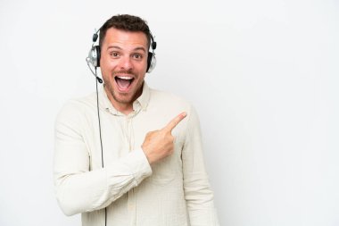 Tele pazarlamacı, beyaz arka planda izole edilmiş bir kulaklıkla çalışan beyaz bir adam şaşırmış ve işaret ediyor.