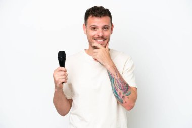 Beyaz arka planda izole edilmiş bir mikrofonu eline alan beyaz tenli genç şarkıcı