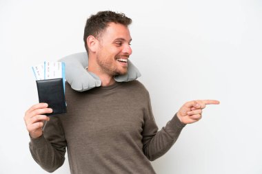 Beyaz arka planda izole edilmiş bir pasaport taşıyan genç beyaz bir adam parmak göstererek bir ürün sunuyor.