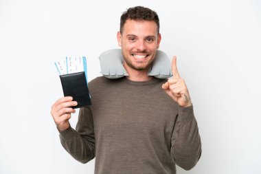 Beyaz arka planda izole edilmiş pasaport taşıyan genç beyaz bir adam en iyinin işareti olarak parmağını kaldırıyor.