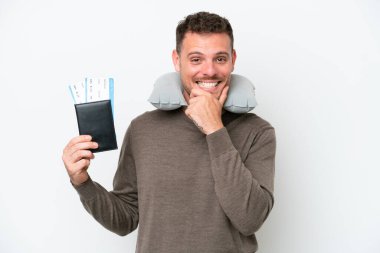Beyaz arka planda izole edilmiş pasaportu olan genç beyaz bir adam mutlu ve gülümsüyor.