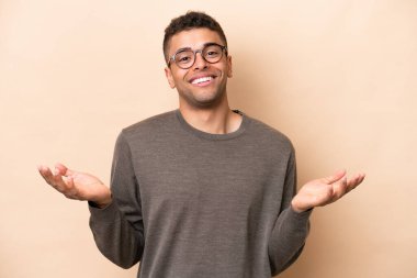 Genç Brezilyalı adam bej arka planda izole edilmiş mutlu ve gülümsüyor