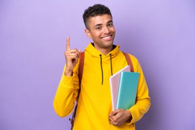 Mor arka planda izole genç Brezilyalı adam en iyinin işareti olarak parmağını kaldırıyor ve gösteriyor.