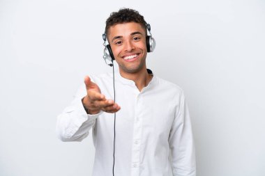 Tele pazarlamacı Brezilyalı adam beyaz arka planda izole edilmiş bir kulaklıkla çalışıyor ve iyi bir anlaşma için el sıkışıyor.