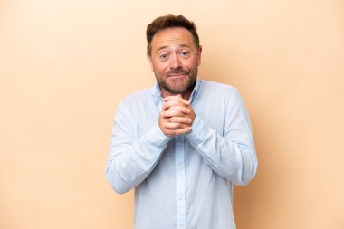 Orta yaşlı beyaz bir adam bej arka planda izole edilmiş gülüyor.