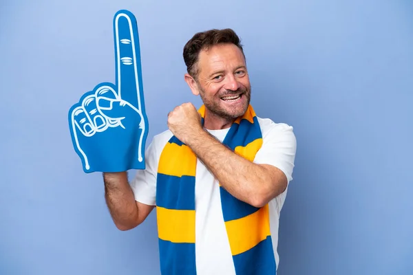Middle age caucasian sports fan man isolated on blue background celebrating a victory