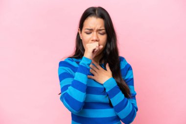 Pembe arka planda izole edilmiş genç Kolombiyalı kadın çok öksürüyor.