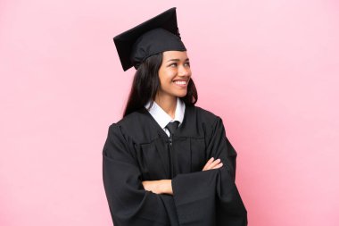 Kolombiyalı genç bir üniversite mezunu pembe arka planda mutlu ve gülümsüyor.