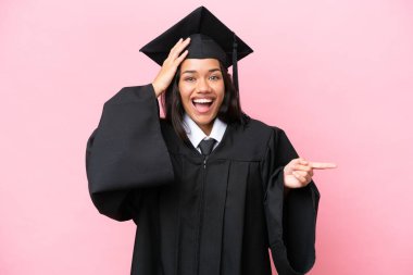 Üniversiteden mezun genç bir Kolombiyalı kadın pembe arka planda izole edilmiş.