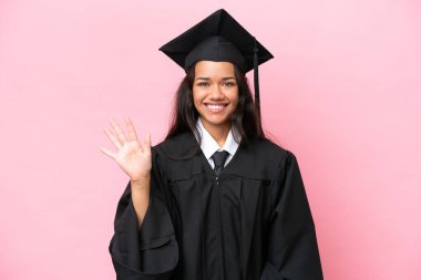 Kolombiyalı genç bir üniversite mezunu. Pembe arka planda izole edilmiş. Parmaklarıyla beşi sayıyor.