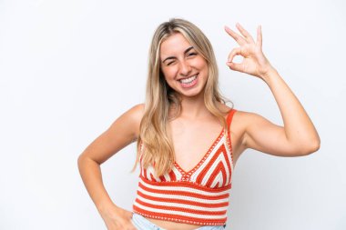 Beyaz arka planda izole edilmiş genç beyaz kadın parmaklarıyla tamam işareti gösteriyor.