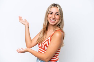 Beyaz arka planda soyutlanmış beyaz tenli genç bir kadın davet edilmek için ellerini yana uzatıyor.