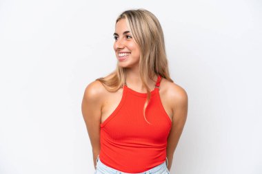 Beyaz arka planda izole edilmiş genç beyaz kadın yan bakıyor ve gülümsüyor.