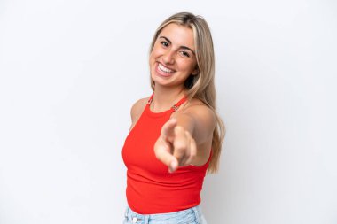 Beyaz arka planda izole genç beyaz kadın mutlu bir ifadeyle ön tarafı işaret ediyor.