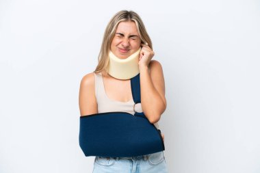 Kırık kollu ve askı takan bir kadın beyaz arka planda hayal kırıklığına uğramış ve kulaklarını kapatmış.