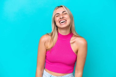 Mavi arka planda izole edilmiş genç beyaz kadın gülüyor.
