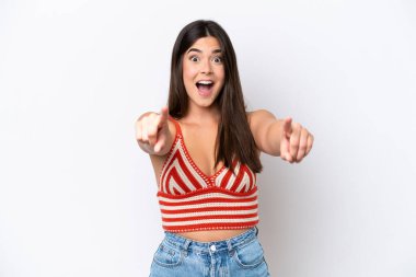 Beyaz arka planda izole edilmiş genç Brezilyalı kadın şaşırmış ve ön tarafı işaret ediyor.