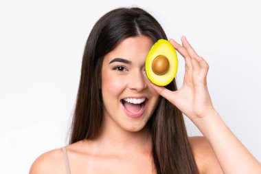 Genç Brezilyalı bir kadın beyaz arka planda izole edilmiş, elinde avakado tutarken gülümsüyor. Portreyi kapat
