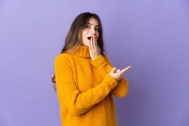 Mor arka planda yalıtılmış beyaz bir kadın, sürpriz bir ifadeyle işaret ederken...