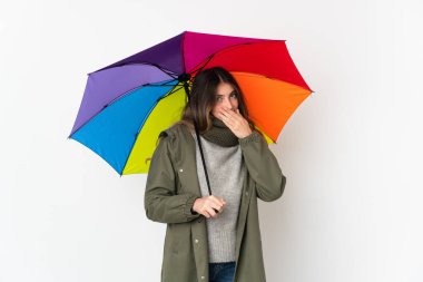 Beyaz arka planda şemsiye tutan genç beyaz kadın mutlu ve gülümsüyor.