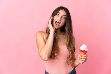 Kornet dondurması olan beyaz bir kadın pembe arka planda izole edilmiş, şaşırmış ve şok olmuş bir yüz ifadesi var.