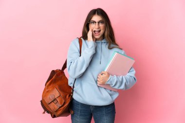 Pembe arka planda izole edilmiş genç bir kadın. Şaşırmış ve şok olmuş bir yüz ifadesi var.