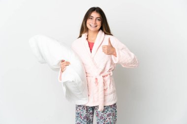 Beyaz arka planda, pijamalı, beyaz tenli genç beyaz bir kadın. Başparmakları havada, çünkü iyi bir şey oldu.