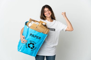 Elinde kağıt dolu bir geri dönüşüm çantası olan genç bir kadın beyaz arka planda izole edilmiş bir şekilde güçlü bir jest yapıyor.