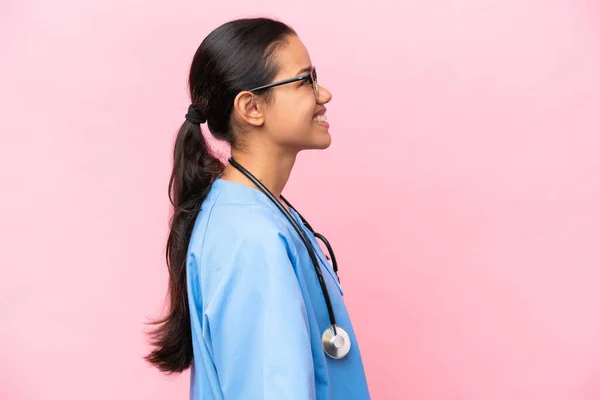 年轻的护士哥伦比亚妇女被隔离在粉红的背景上 侧身笑着 — 图库照片