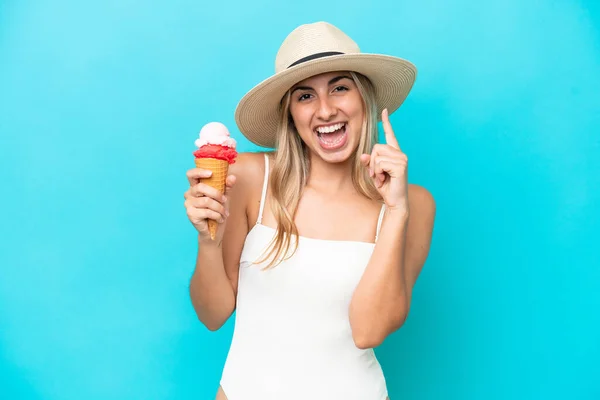 若いですCaucasian女性で水着とともにCornetアイスクリーム孤立上の青の背景指摘素晴らしいアイデア — ストック写真