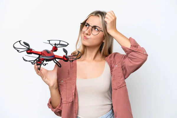 Woman holding a drone over isolated background having doubts and with confuse face expression