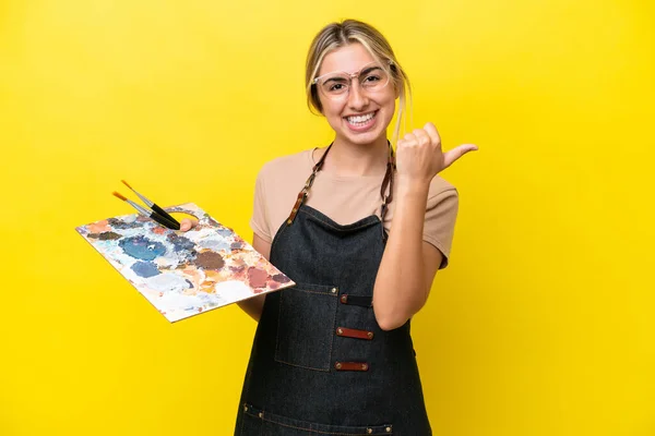 Jovem Artista Caucasiana Segurando Uma Paleta Isolada Fundo Amarelo Apontando — Fotografia de Stock