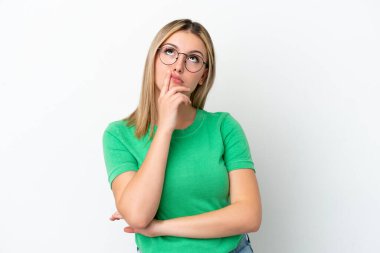 Beyaz arka planda izole edilmiş genç beyaz kadın yukarı bakarken şüpheleri var.