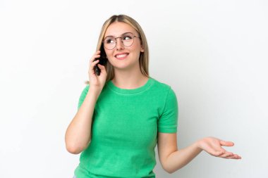 Beyaz arka planda izole edilmiş genç beyaz bir kadın cep telefonuyla sohbet ediyor.