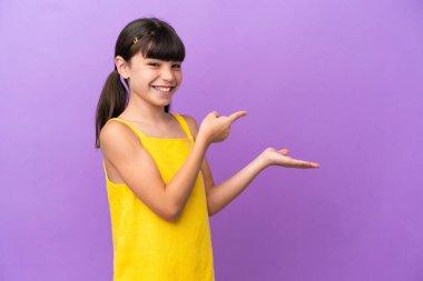 Mor arka planda izole edilmiş küçük beyaz çocuk, bir ilan vermek için avuç içinde hayali bir mekan tutuyor.