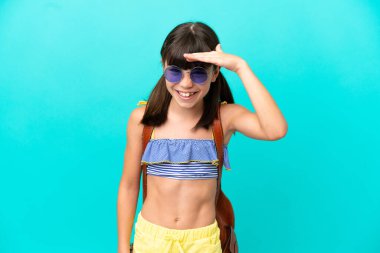 Küçük beyaz bir çocuk kumsala gidiyor. Mavi arka planda izole edilmiş. Bir şeye bakmak için uzaklara bakıyor.