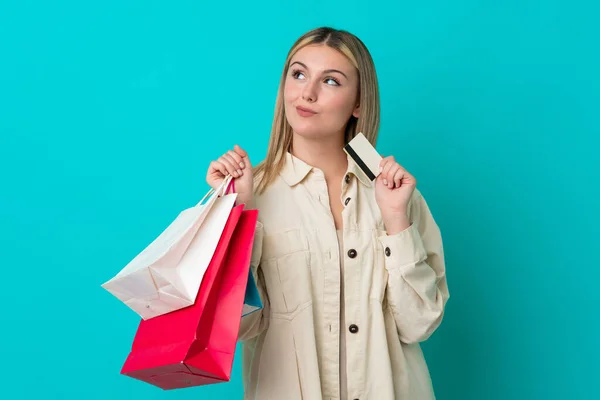 Jonge Blanke Vrouw Geïsoleerd Blauwe Achtergrond Met Boodschappentassen Een Creditcard — Stockfoto