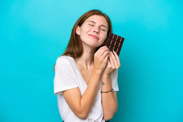 Jovem Inglesa Isolada Fundo Azul Tomando Comprimido Chocolate Feliz — Fotografia de Stock