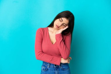 Kafkasyalı genç bir kadın mavi arka planda izole edilmiş, baş ağrısı var.